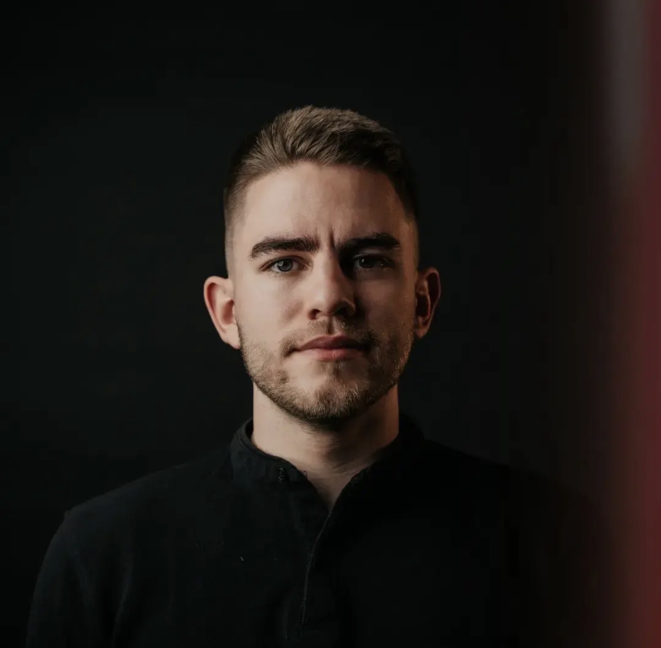 Portret moškega v črni srajci pred temnim ozadjem